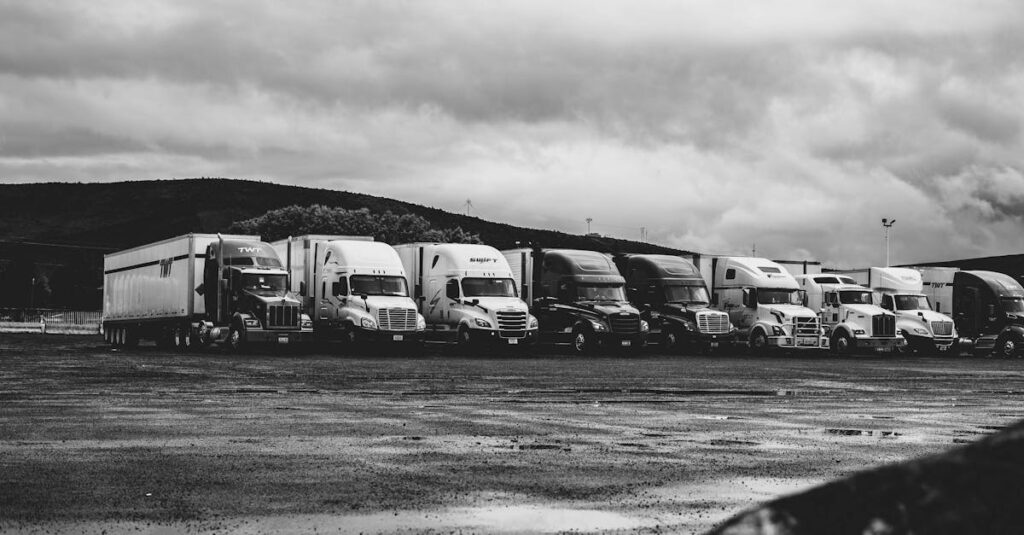 Row of parked semi trucks in a rainy lot, captured in a dramatic black and white setting.